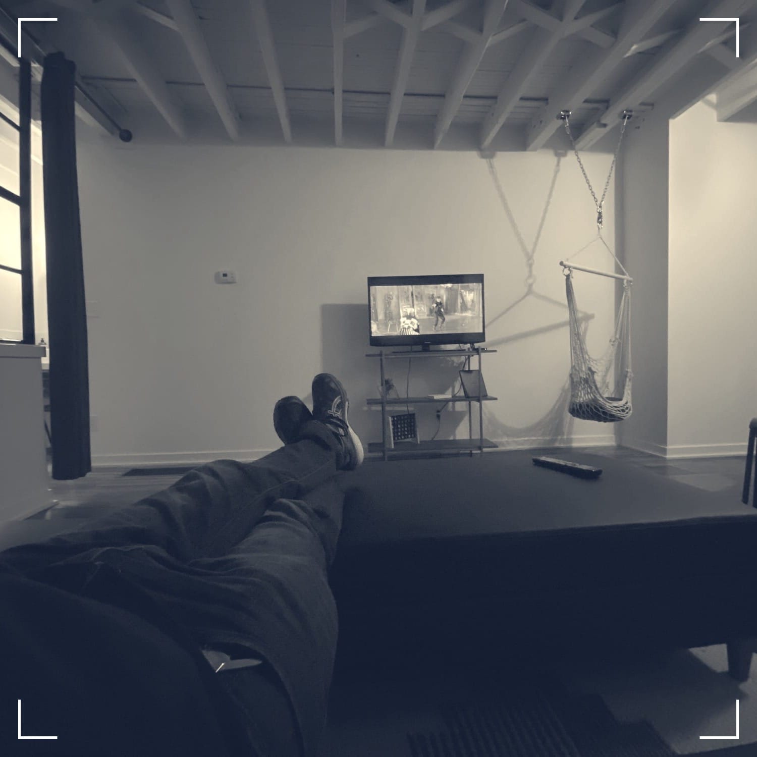 feet up on a tv table in an otherwise vacant apartment, watching a small tv